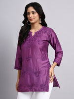 Side view of Woman wearing a purple embroidered kurta against a gray background