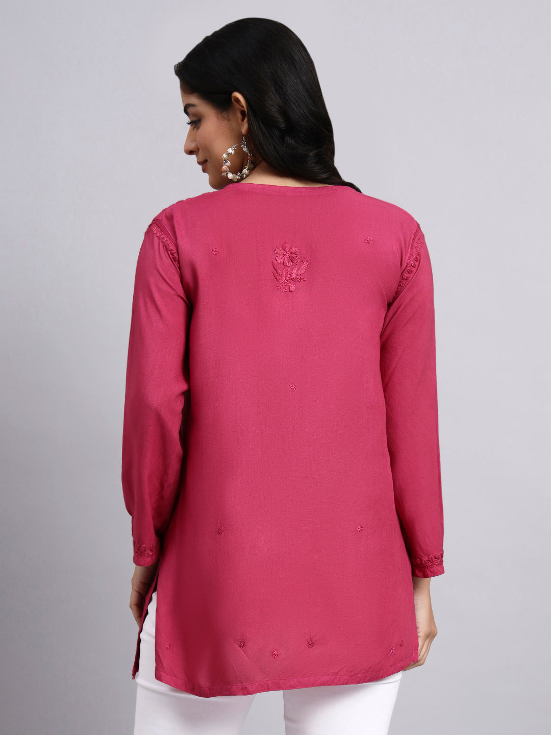 Back view of Woman wearing a pink long-sleeve short kurti with a subtle design on a gray background