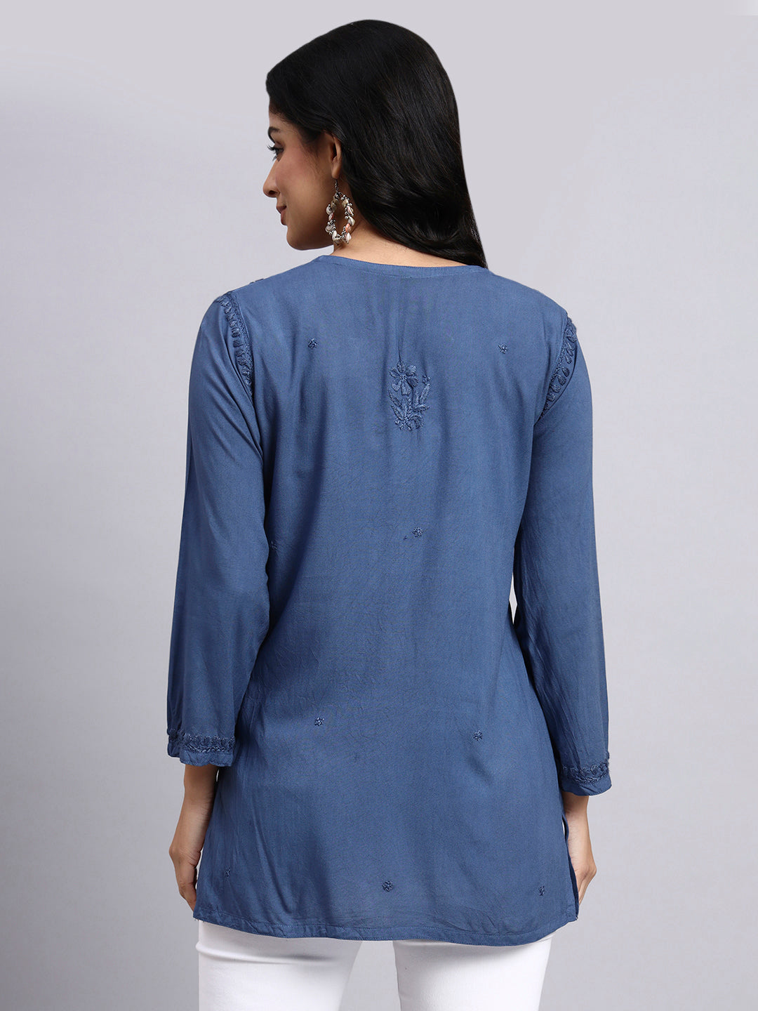 Back view of Woman wearing a blue kurta with white pants on a gray background.