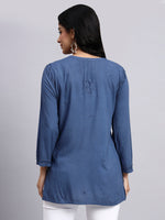 Back view of Woman wearing a blue kurta with white pants on a gray background.