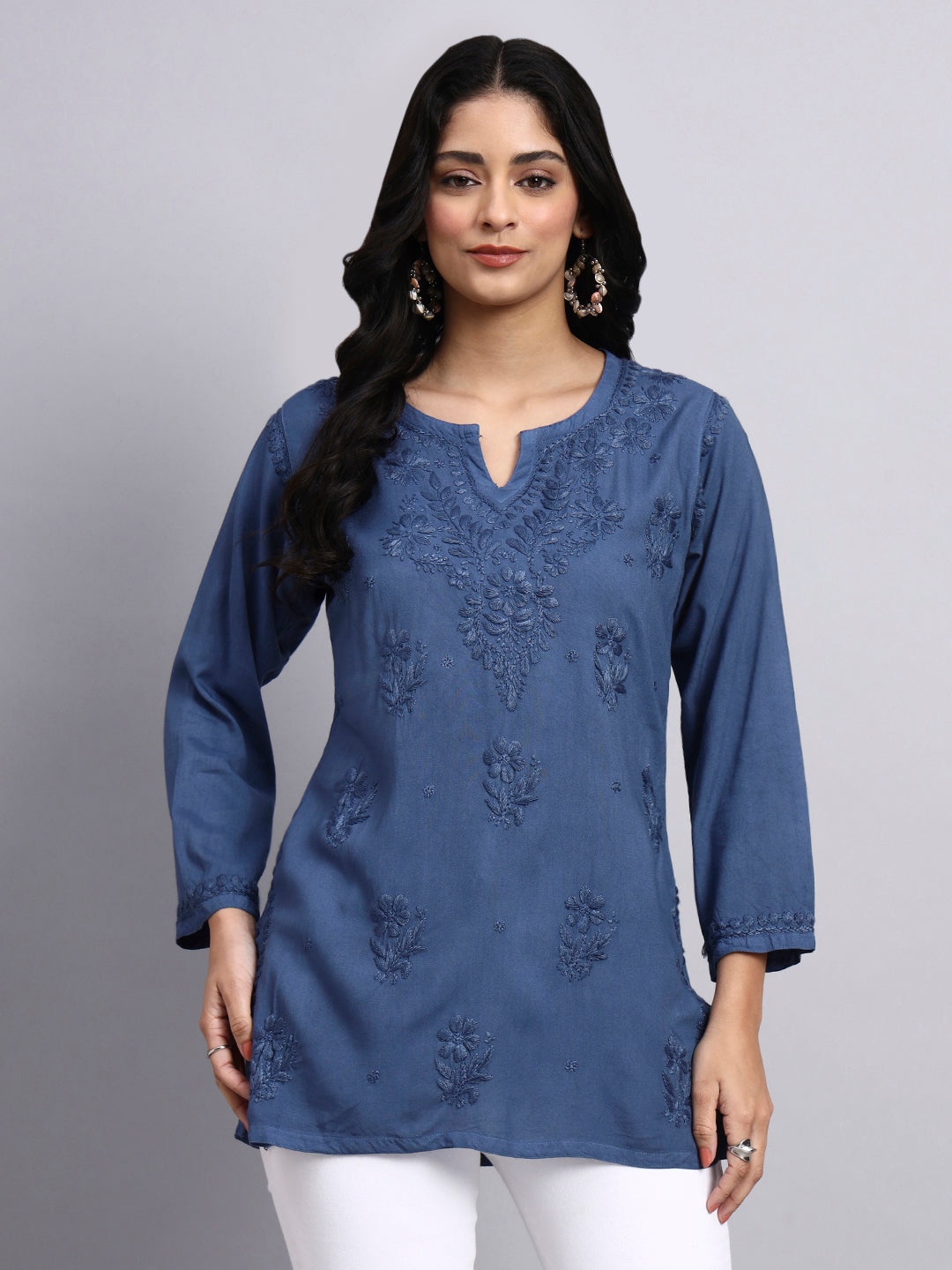 Front view of Woman wearing a blue embroidered chikankari kurti against a gray background