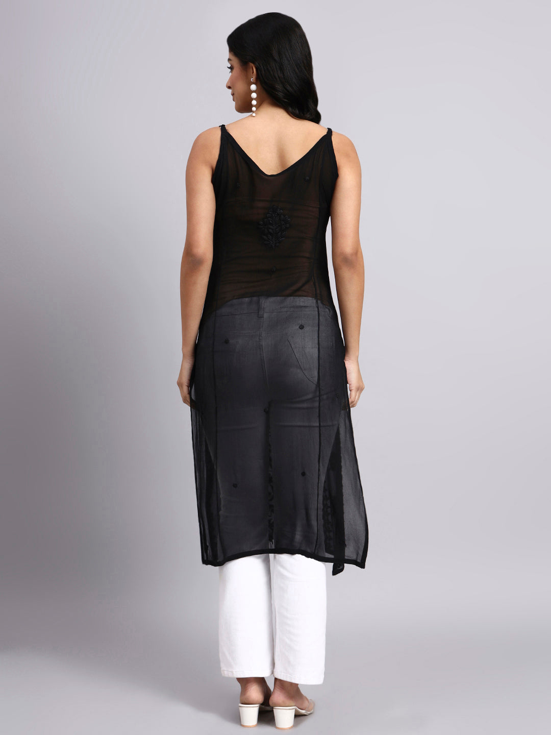 Back view of Woman wearing a black sleeveless kurti with white pants on a gray background