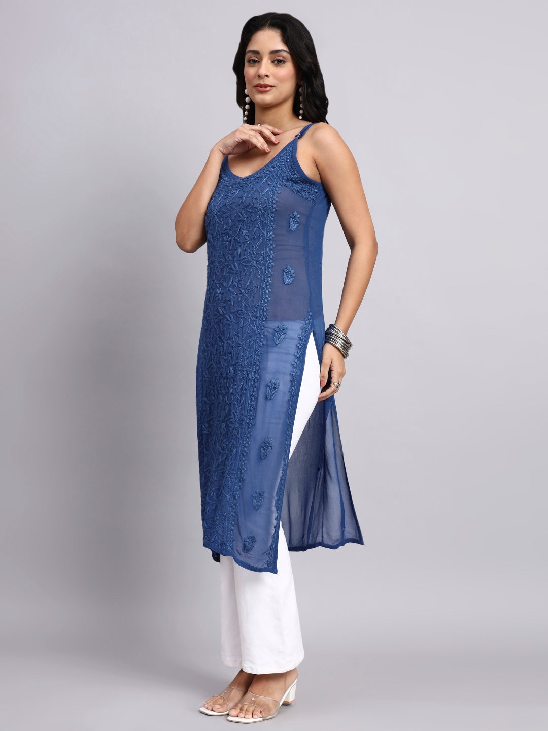 Woman wearing a blue embroidered chikankari kurti with white pants on a gray background