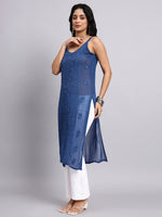 Woman wearing a blue embroidered chikankari kurti with white pants on a gray background