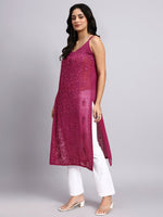 Side dress of Woman wearing a long rani pink embroidered dress with white pants on a gray background