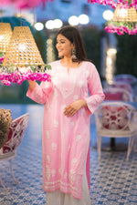 Side view of a woman gracefully posing in a stylish pink Lucknow Chikan kurta featuring exquisite white traditional embroidery.