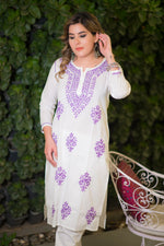 Angled view of a woman wearing a white mulmul kurta with intricate purple threadwork.