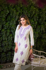 Slight close-up of the purple floral and leaf embroidery on a stylish white chikankari kurta.