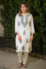 Front view of a woman in a white chikankari kurta with black traditional embroidery.