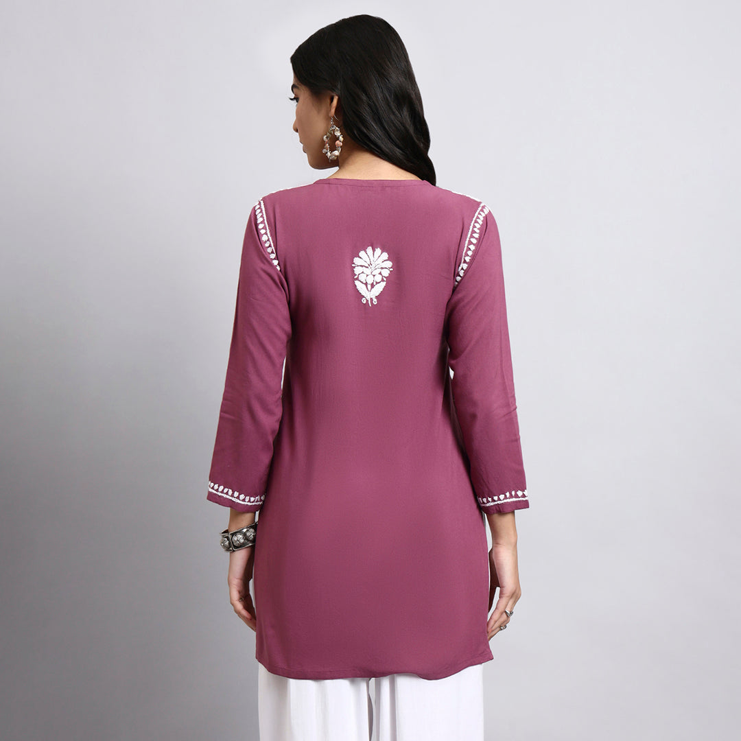 Purple traditional outfit with white floral embroidery on a gray background