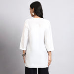 Women wearing a white long-sleeve top against a gray background.