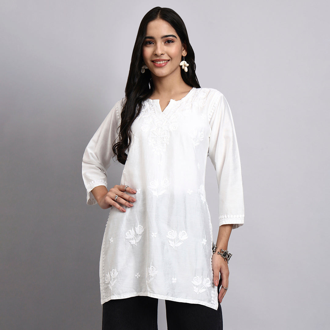 Woman wearing a white floral blouse against a gray background