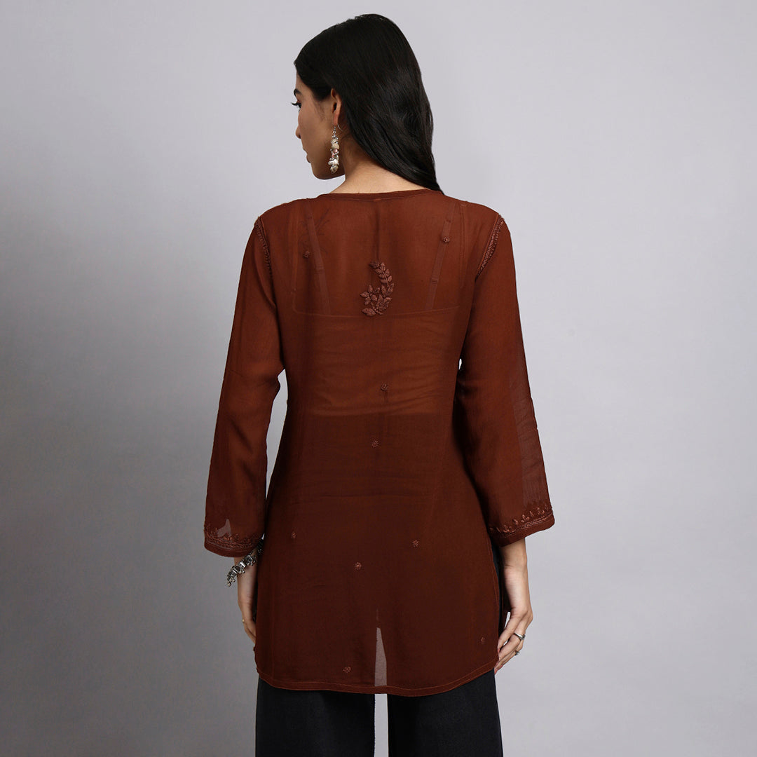 Back View Of Woman wearing a brown long-sleeve top with a subtle design on a gray background