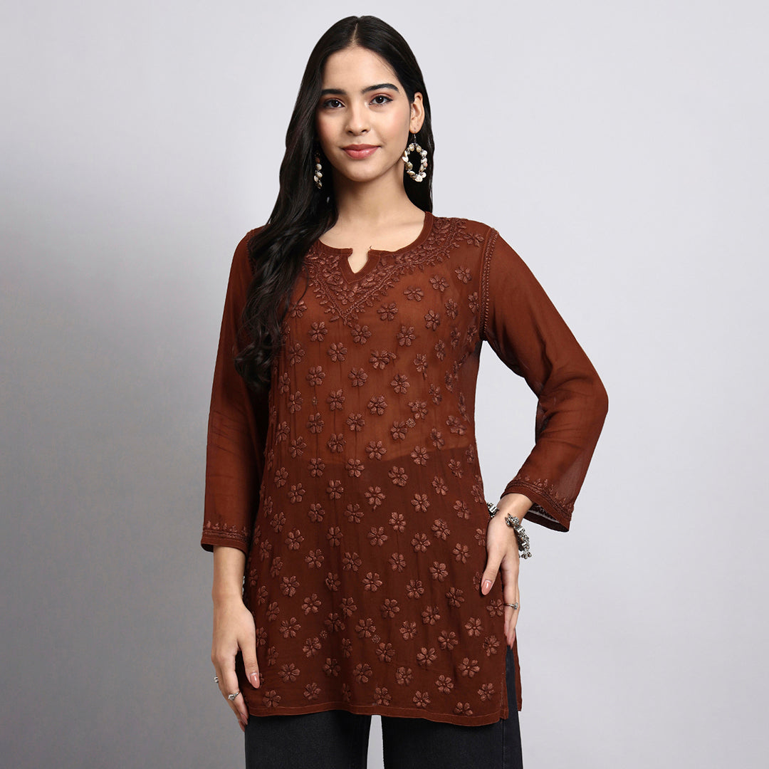 Woman wearing a brown embroidered kurta against a gray background