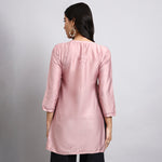 Back view of Woman wearing a pink kurta with 3/4 sleeves on a plain background