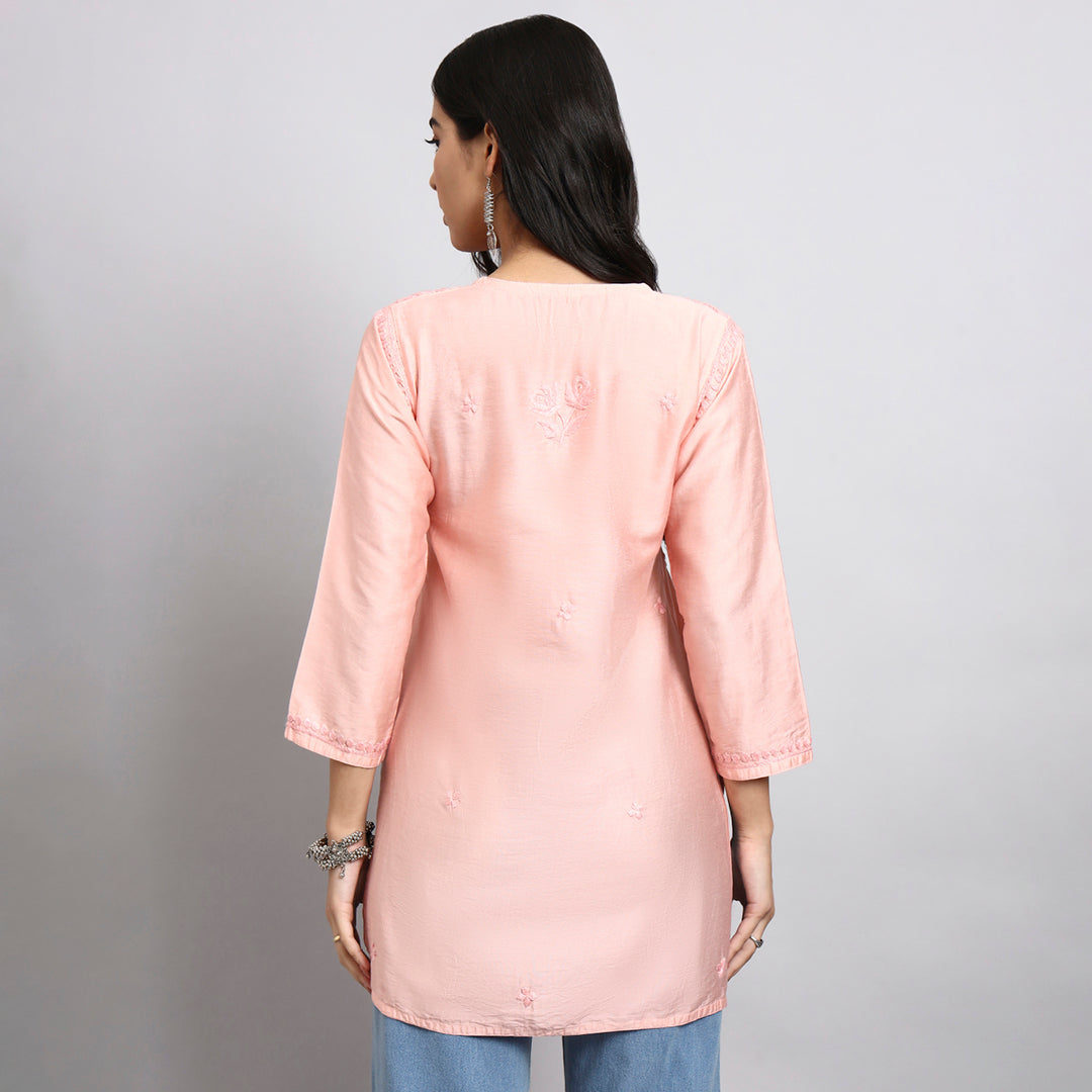Back View of Woman wearing a light pink kurta with blue pants on a gray background