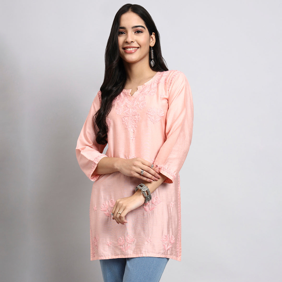 Woman wearing a pink kurta with floral patterns on a gray background