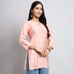Woman wearing a pink kurta with blue pants on a gray background