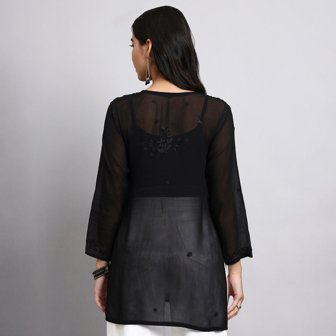 Back view of wearing a black sheer short kurta with a plain background