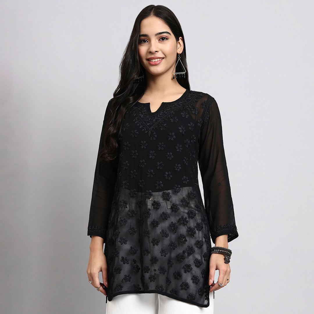 Woman wearing a black floral patterned short kurta on a gray background.