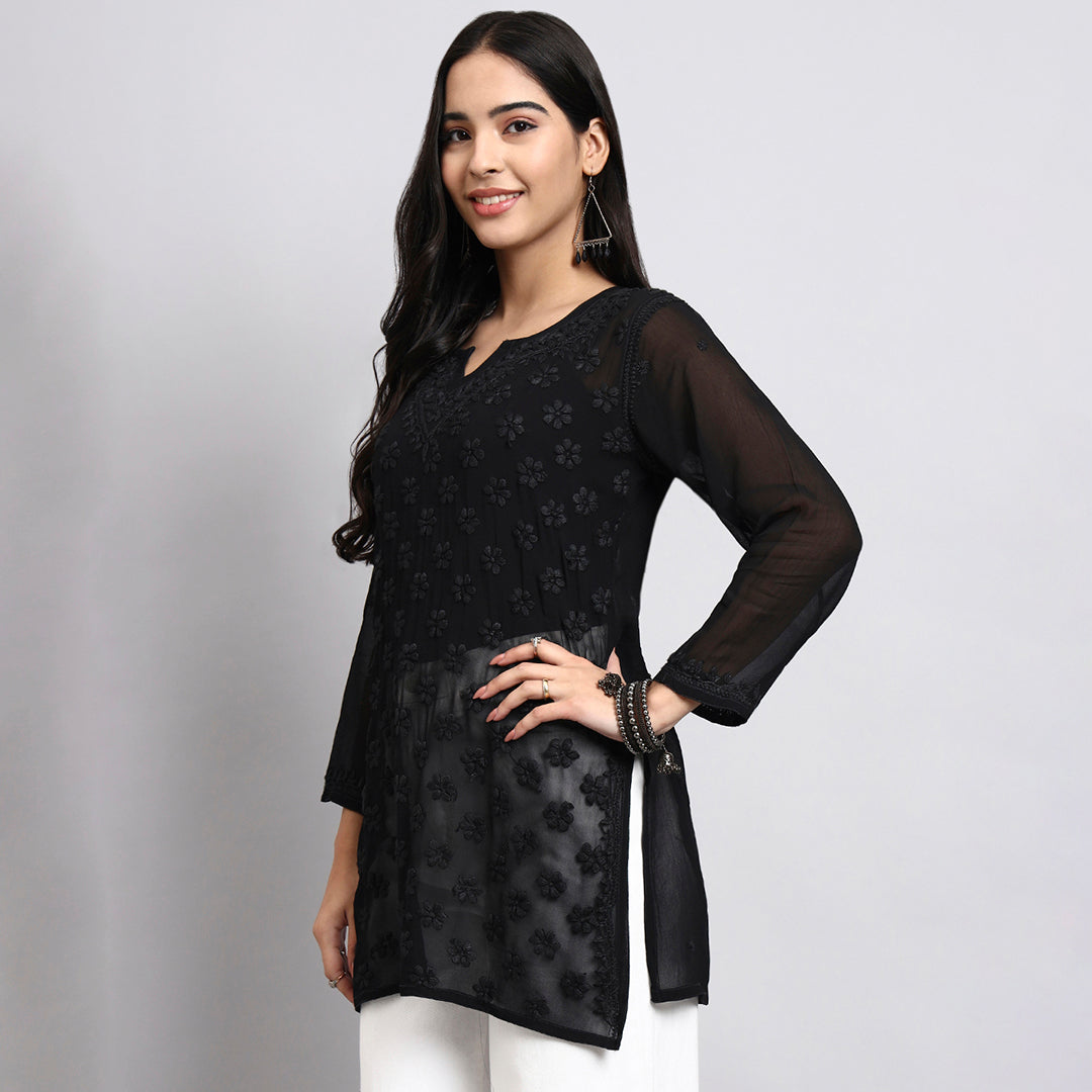 Woman wearing a black floral patterned short kurta on a gray background