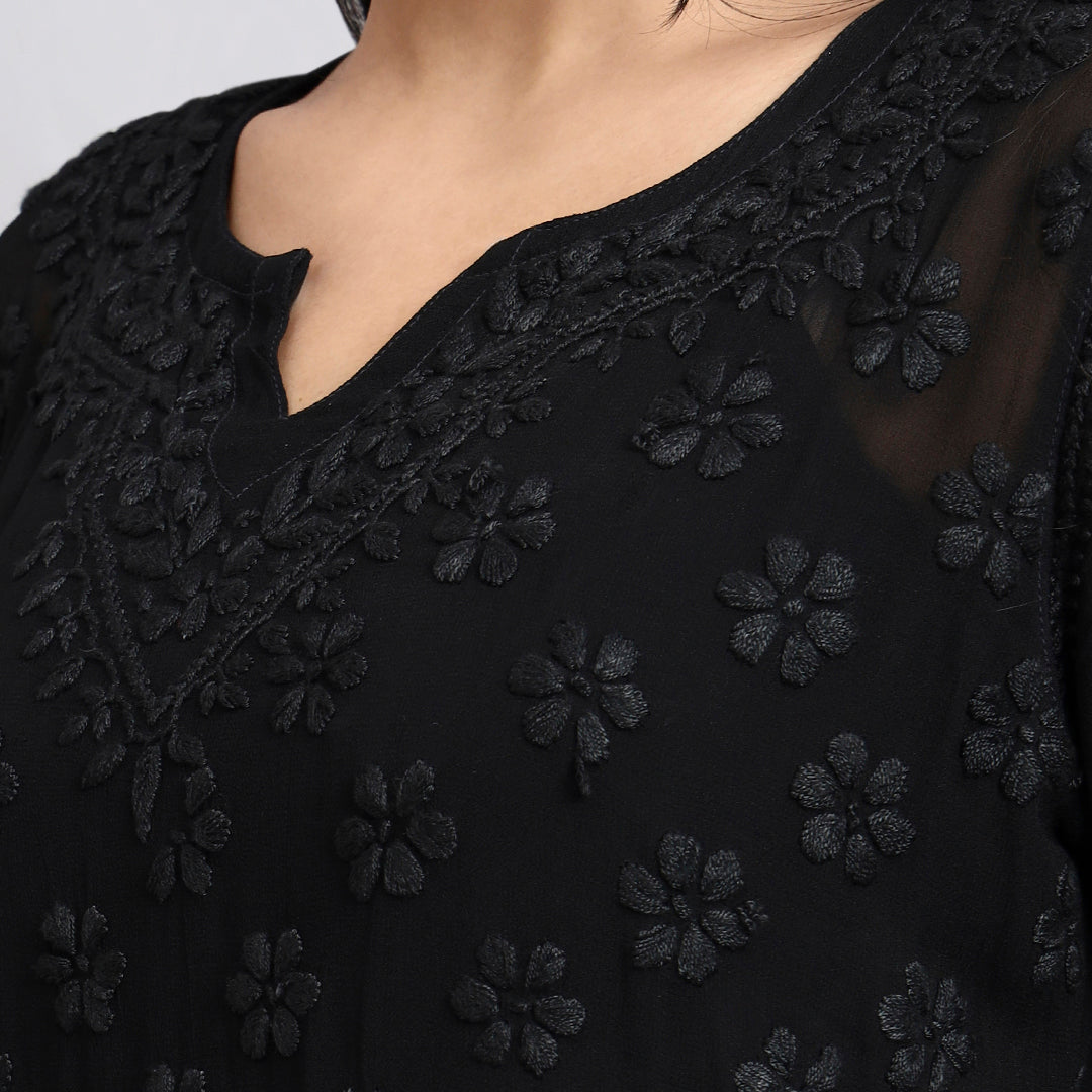 Zoom view of Black embroidered garment with floral patterns on a plain background