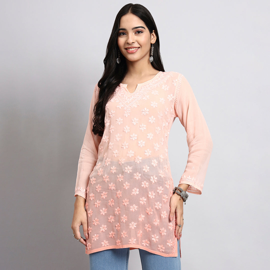 Woman wearing a light pink floral top against a gray background.