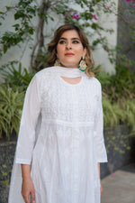 Frontal view of a woman looking up, dressed in a long, plain white Indian kurti. 