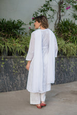 Back view of a woman in a white anarkali kurta with a straight cut, worn with white pants and a draped white scarf. 