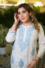White cotton chikankari kurta displayed from a slanted front angle with clear embroidery details.
