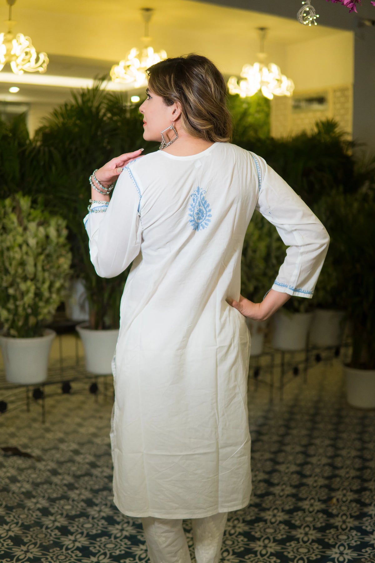 Back pose of a festive white chikankari kurta showcasing full embroidery in blue across the outfit.