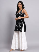 Side view of Woman wearing a black and white patterned top with a white skirt on a gray background
