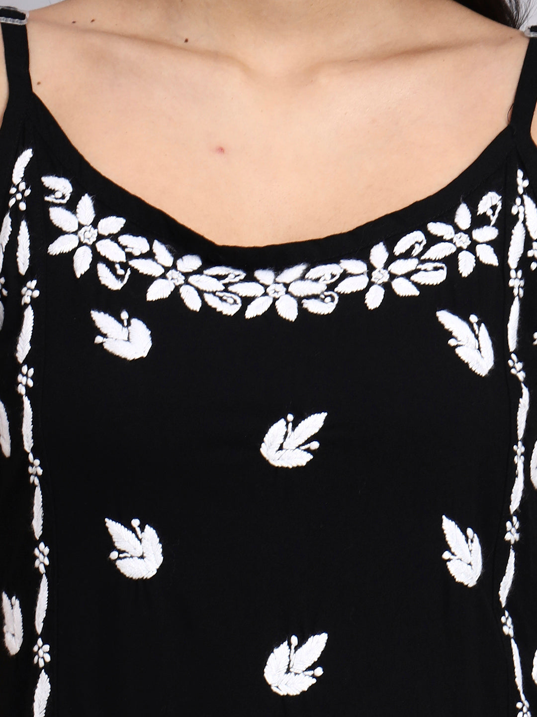 Close up view of Black top with white floral patterns on a plain background
