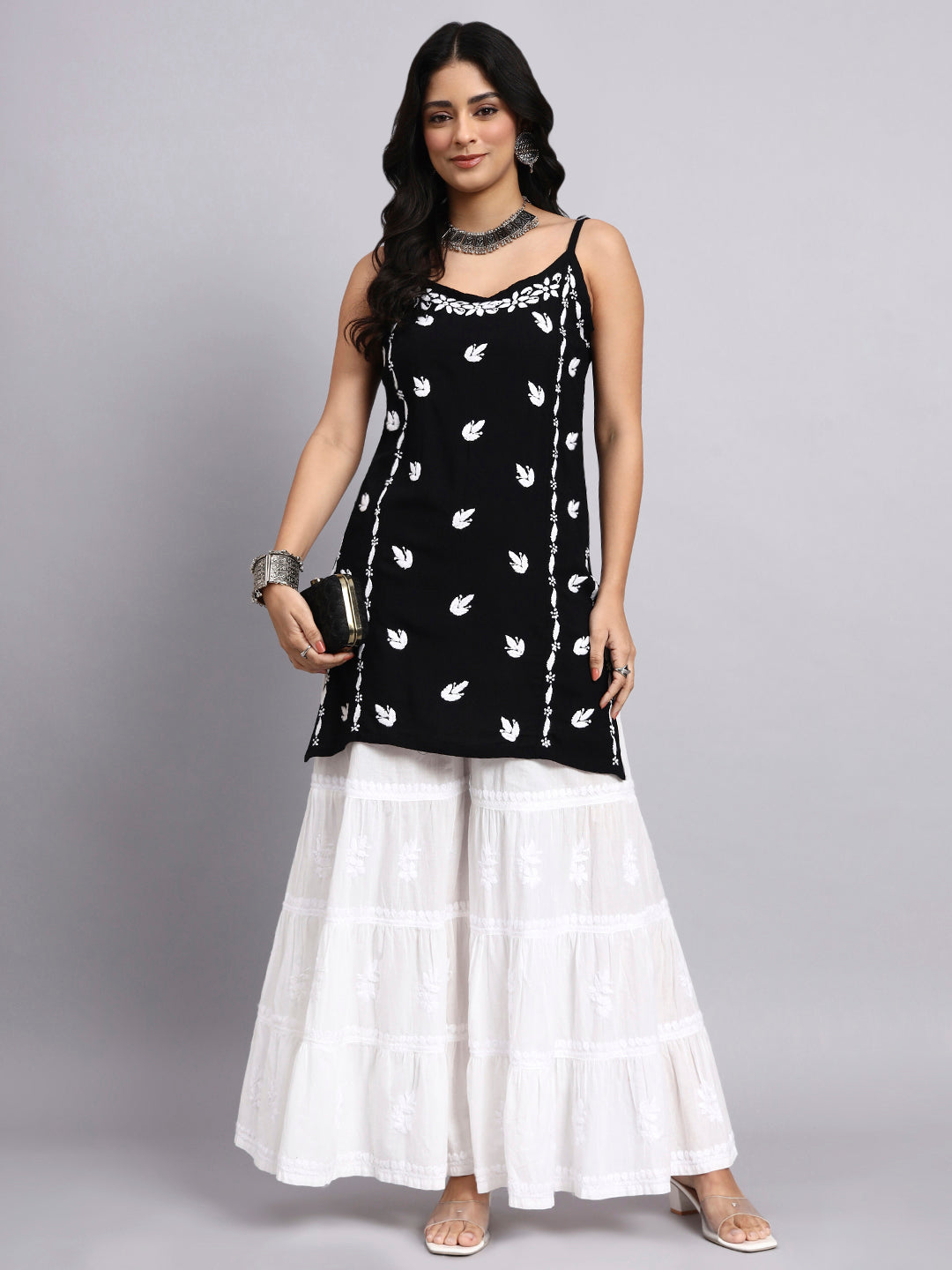 Woman wearing a black and white kurta with sharara with a gray background