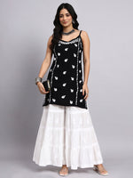 Woman wearing a black and white kurta with sharara with a gray background