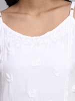 Close-up of a white top with delicate embroidery on a plain background