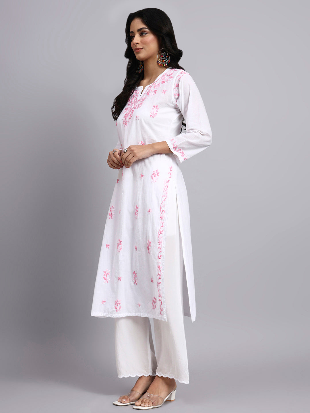 Side view of Woman wearing a white cotton kurta with pink floral embroidery on a gray background