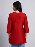 Back view of Woman wearing a red kurta against a gray background