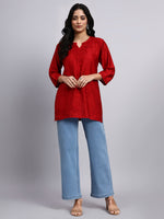 Full view of Woman wearing a red short kurti and blue jeans on a gray background