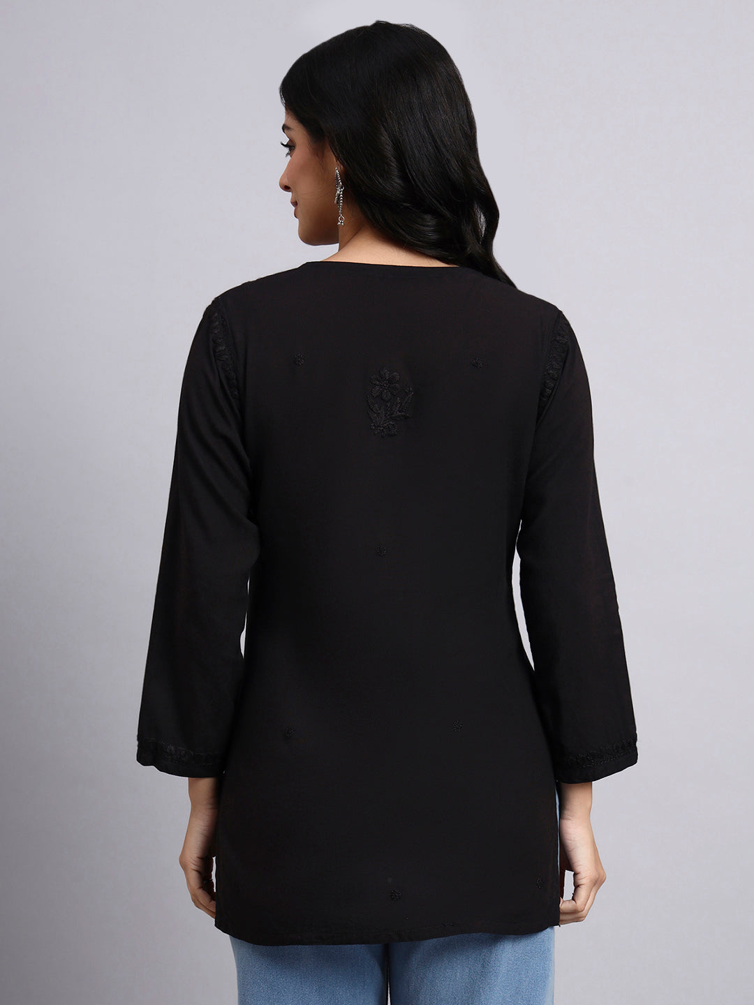 Back view of Woman wearing a black long-sleeve top against a gray background