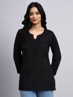 Woman wearing a black long-sleeve short kurti with floral patterns on a gray background