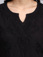 Close up view of Black top with intricate lace detailing on a plain background