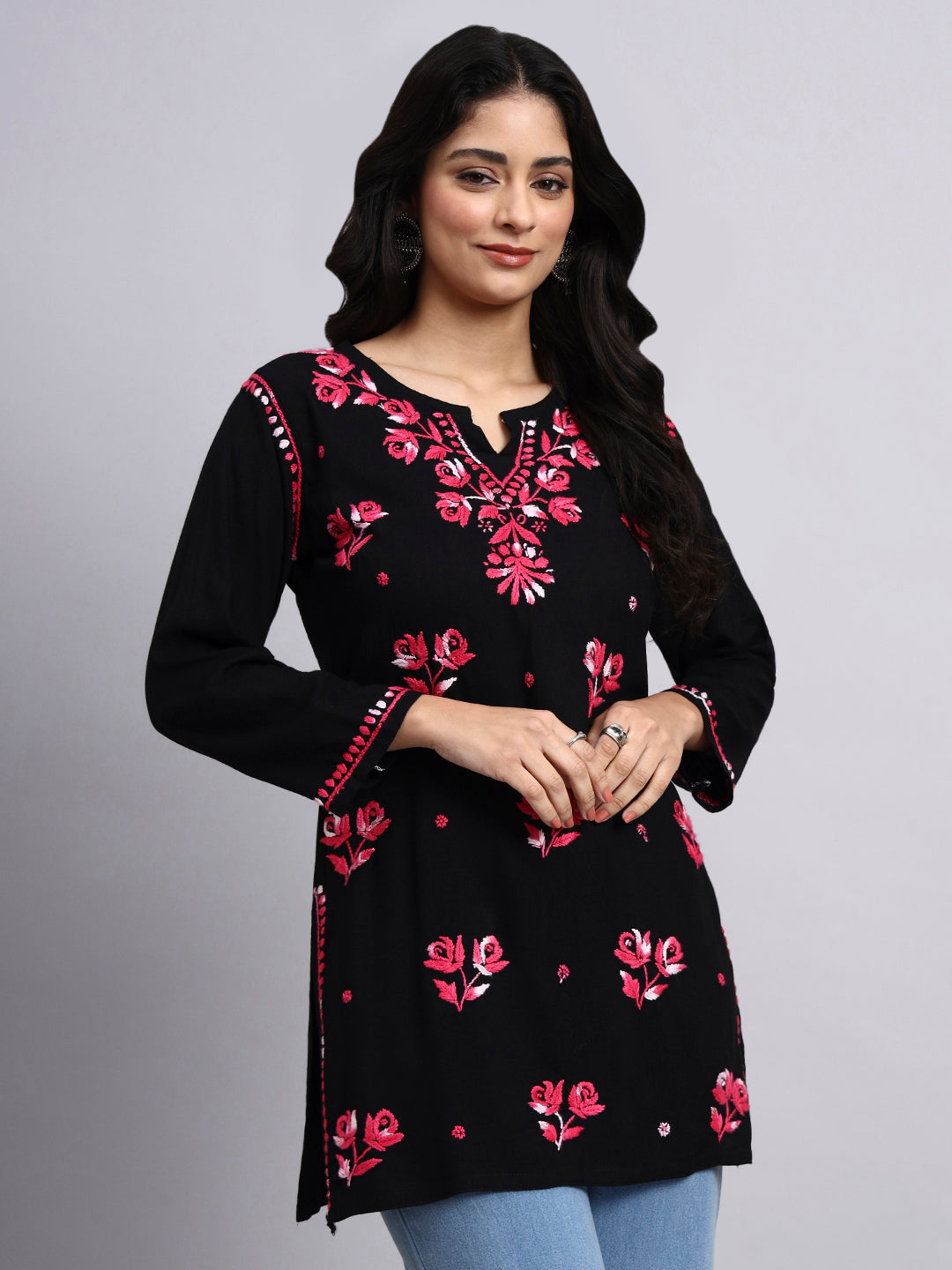 Woman wearing a black kurta with pink floral embroidery on a gray background