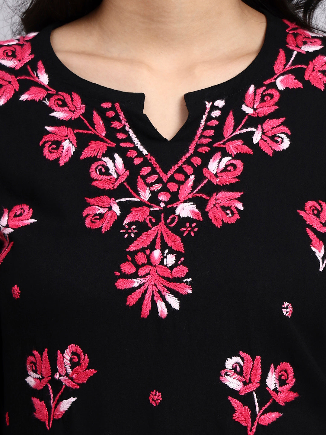 Close up view of Black garment with pink floral embroidery