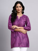 Woman wearing a purple embroidered kurta against a gray background
