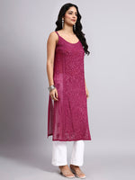 Woman wearing a rani pink embroidered kurta with white pants on a gray background