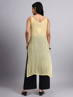 Back view of Woman wearing a light yellow sleeveless top with black pants on a gray background