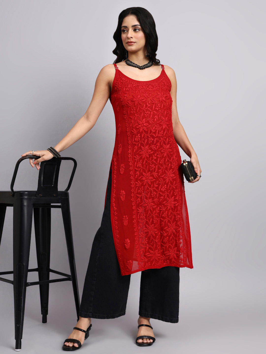 Woman wearing a red sleeveless kurta and black pants against a gray background