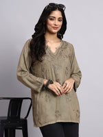 Front view of Woman wearing a olive embroidered top with black pants on a gray background