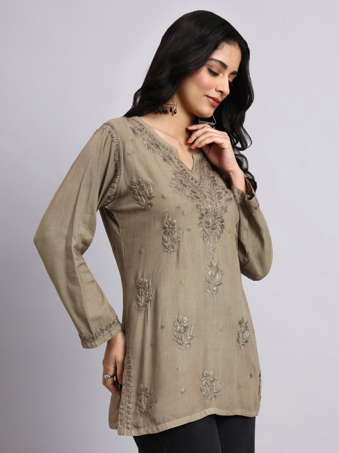 Woman wearing a olive embroidered short kurti on a gray background